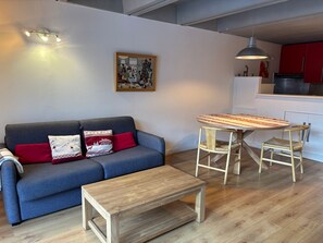 Uma sala de estar moderna com um sofá cinzento, uma mesa de centro de madeira e uma mesa de jantar com cadeiras.