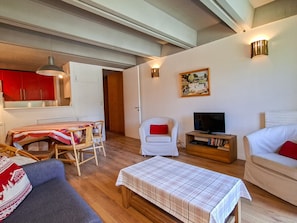 A living room with a sofa, a table, a TV stand, and a dining area with a table and chairs.