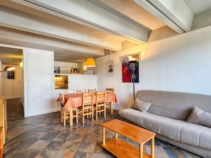 Una sala de estar con un sofá, una mesa de centro de madera y un comedor con mesa y sillas.