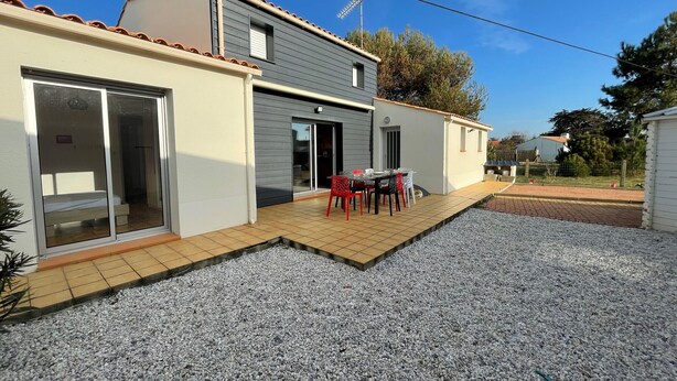 Una casa de dos pisos con un patio que tiene una mesa y sillas.