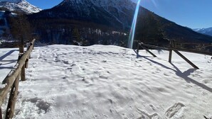 Eine verschneite Berglandschaft mit einem Holzzaun und klarem Himmel.
