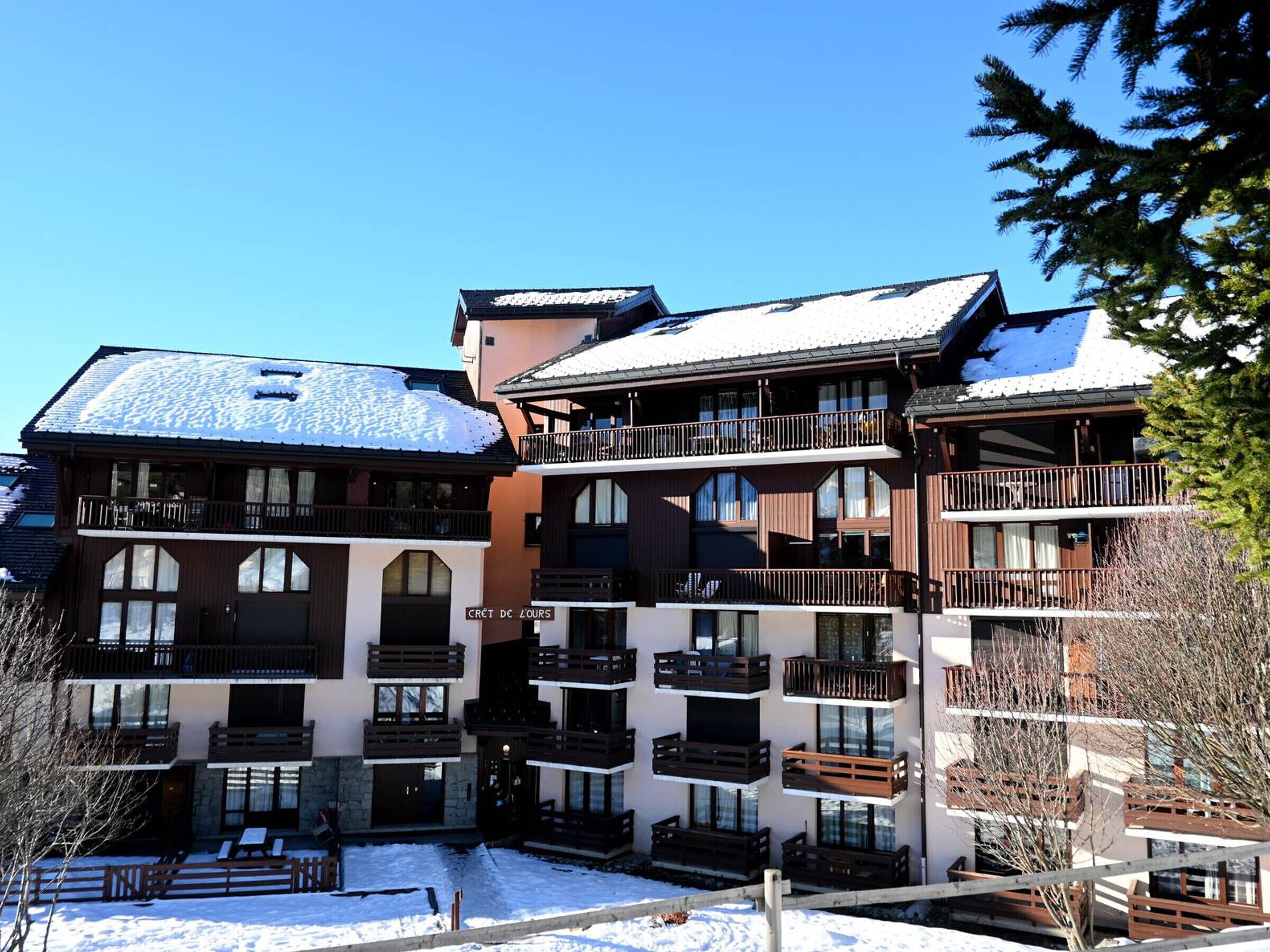 A multi-story hotel with balconies, a snow-covered roof, and a clear sky.