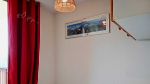 A bedroom with a bed, red curtains, a framed picture on the wall, and a wooden headboard. - Cozy 2-room in Vallandry, 4 guests, near slopes and shops (Peisey-Vallandry)