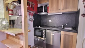 A compact kitchen with wooden cabinets, a microwave, a toaster oven, a dishwasher, and a sink. - Cozy 2-room in Vallandry, 4 guests, near slopes and shops (Peisey-Vallandry)