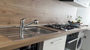 A modern kitchen with a wooden countertop, stainless steel sink, gas stove, and built-in dishwasher.