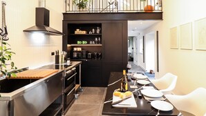 A modern kitchen with a central island, black cabinets, and a dining area with white chairs. - The Pump House Forge (Doncaster)