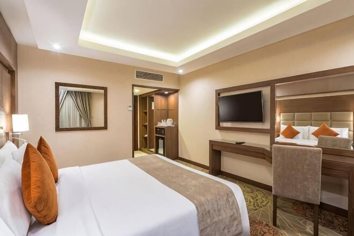 A hotel room with a bed, a TV, a desk, and a chair.