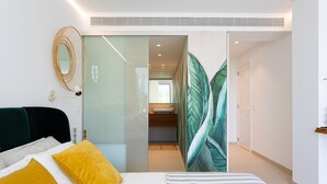 Een moderne slaapkamer met een bed, een bedlamp en een spiegel aan de muur.