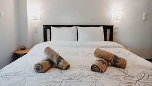 Una cama bien hecha con una colcha de motivos florales y dos toallas enrolladas con diseño de tigre.