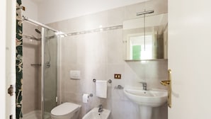 Une salle de bain moderne dotée d’une douche à parois de verre, d’un bidet, de toilettes et d’un lavabo.