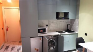 A compact kitchen with a microwave, sink, and washing machine.