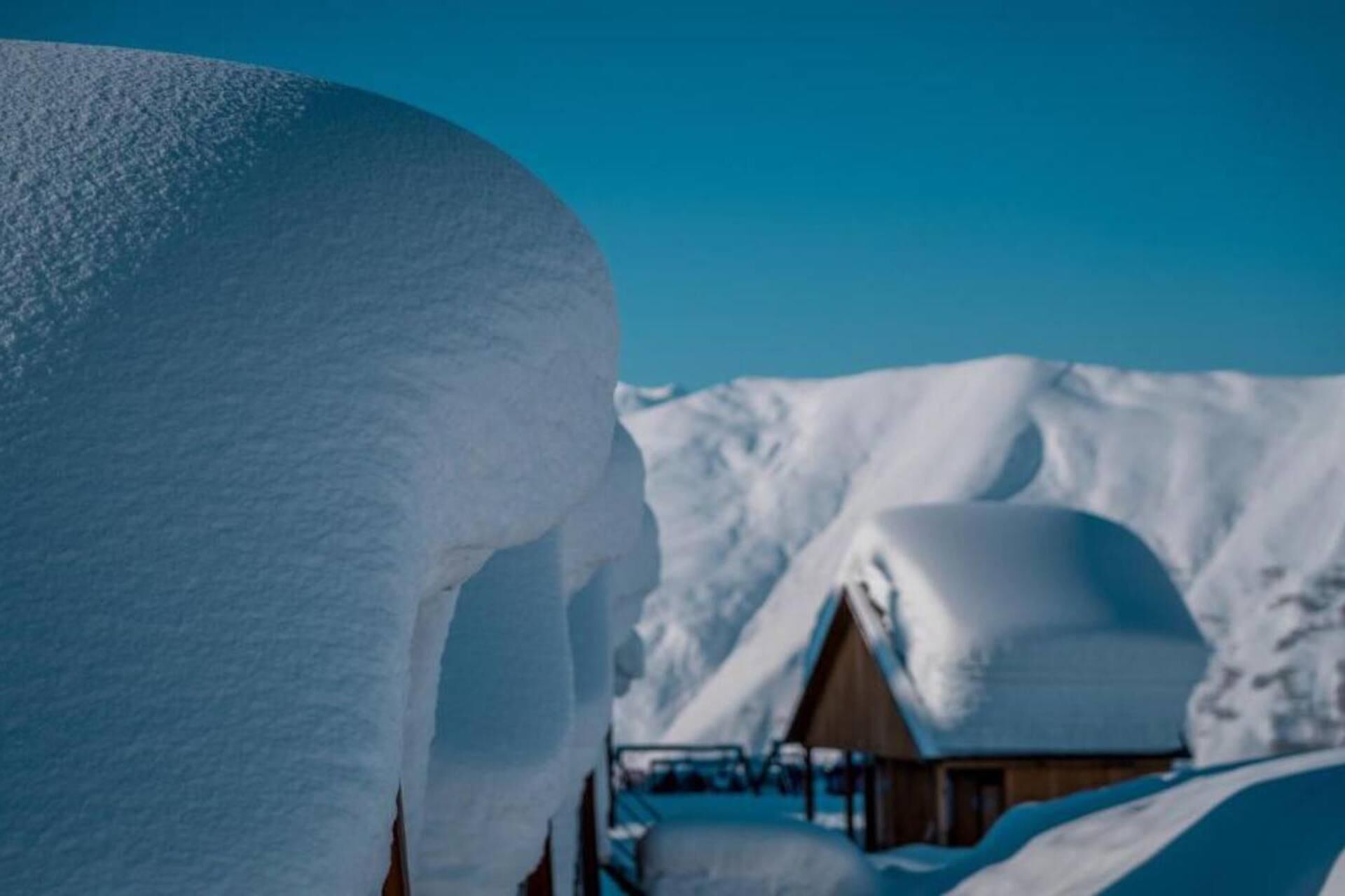 Paesaggio innevato con una baita di legno.