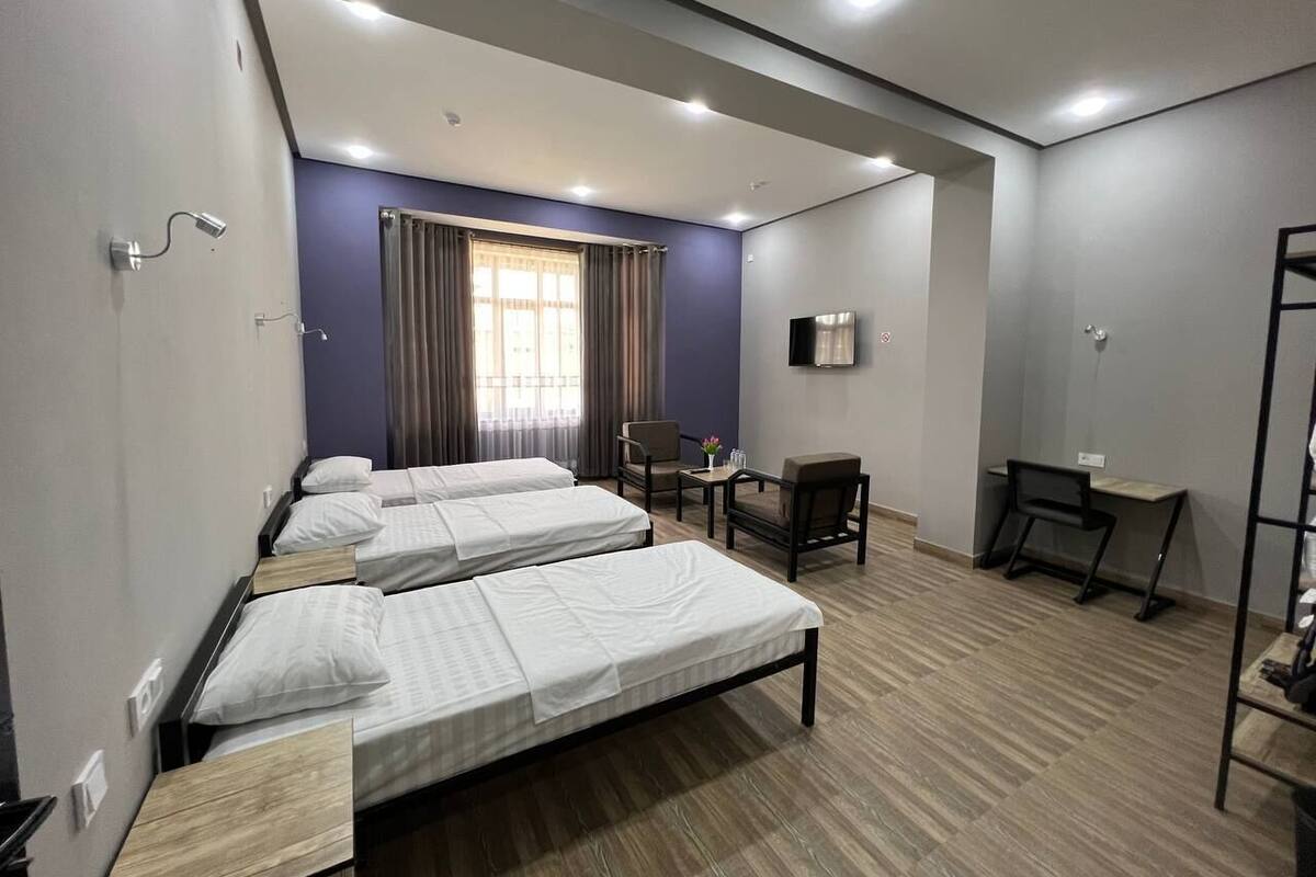 A hotel room with two single beds, a desk, a chair, and a TV.