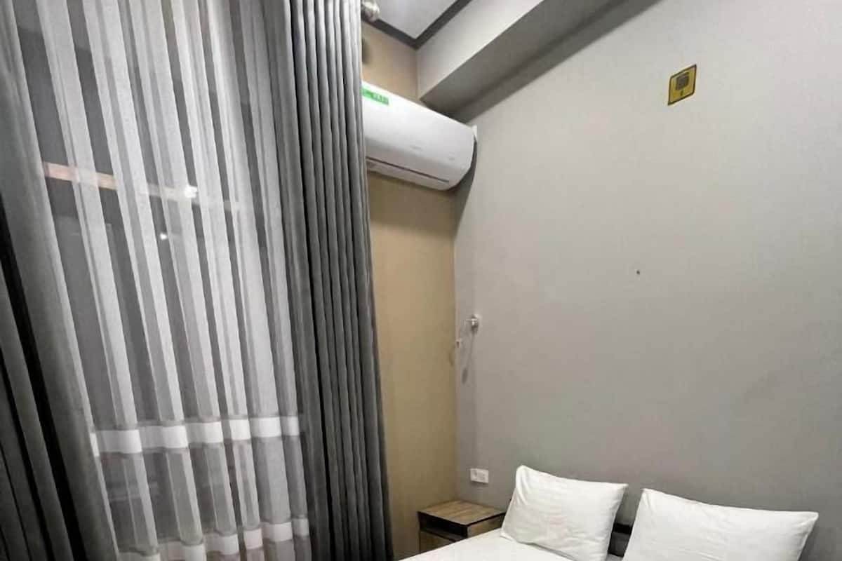 A hotel room with a large bed, two pillows, and two rolled towels on the bed.