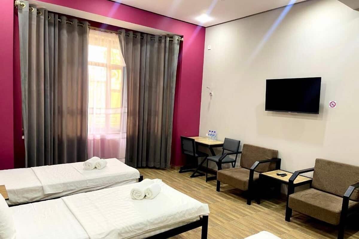 A hotel room with two beds, a TV, a desk, and a seating area.