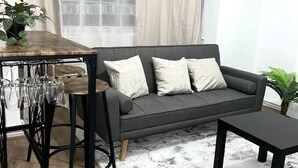 Un salon moderne avec un canapé gris, une table basse en bois et un tabouret de bar.
