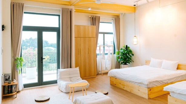 A modern bedroom with a large bed, a small seating area, and a wardrobe. - X-Stay (Hai Phong)