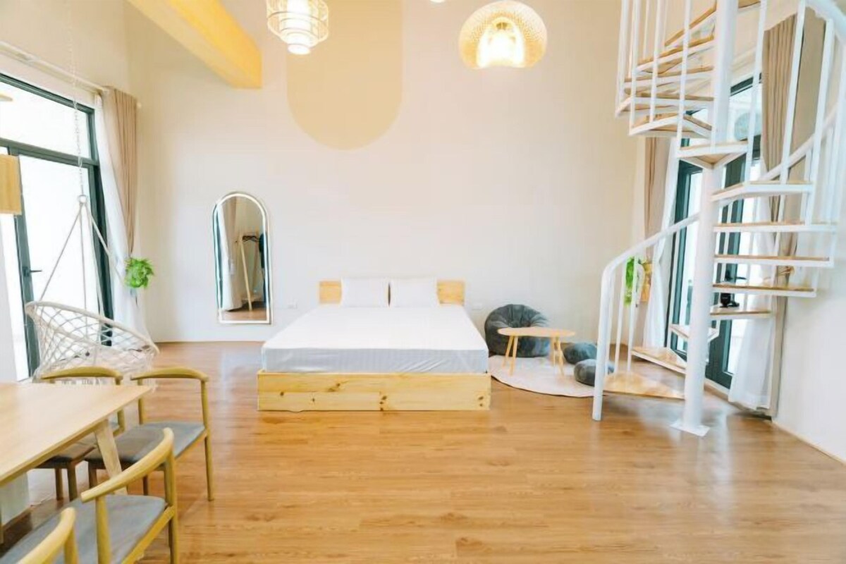Un dormitorio moderno con una cama de madera, una escalera de caracol y un comedor con mesa y sillas.