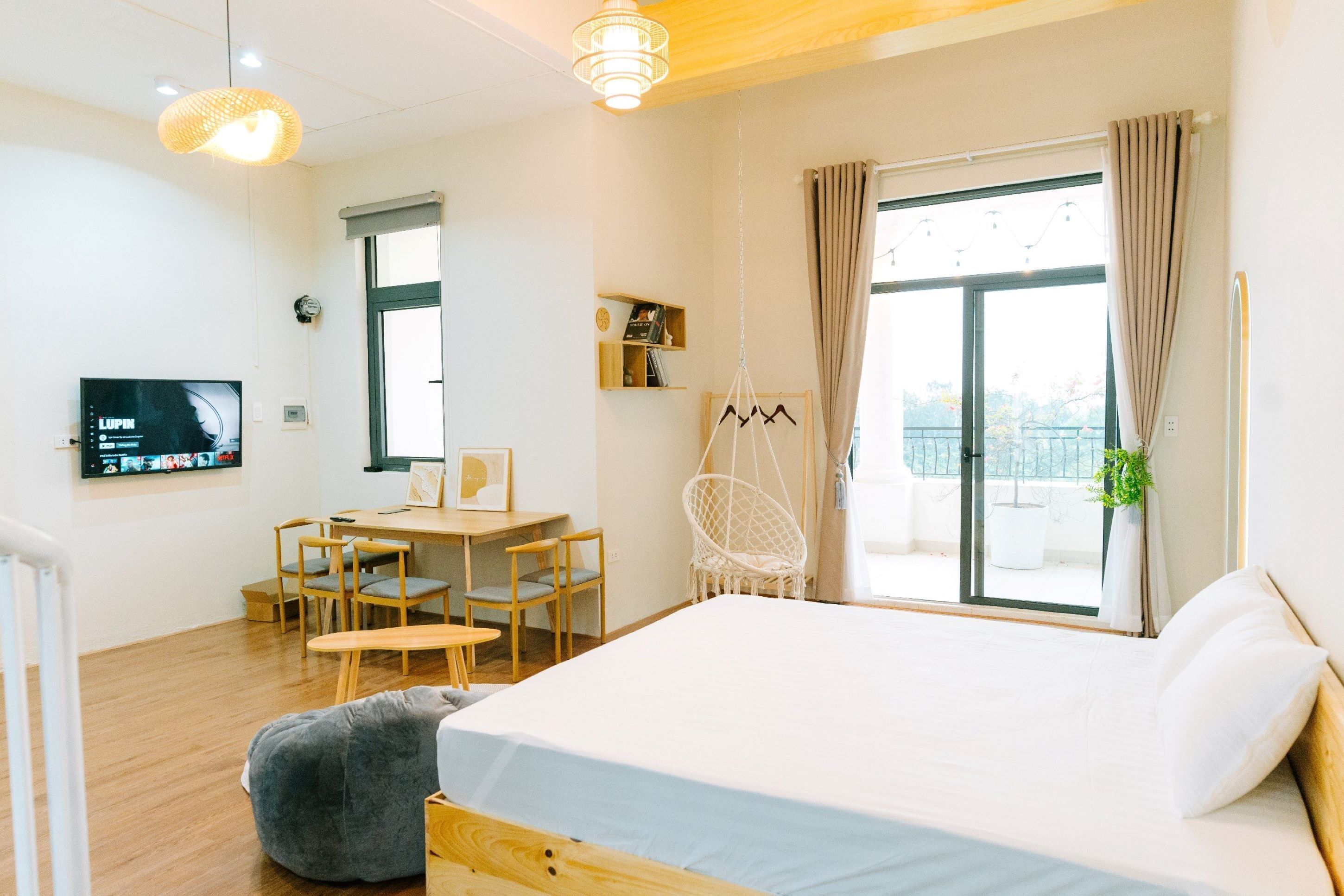 A modern hotel room with a large bed, wooden furniture, a desk, and a TV on the wall.