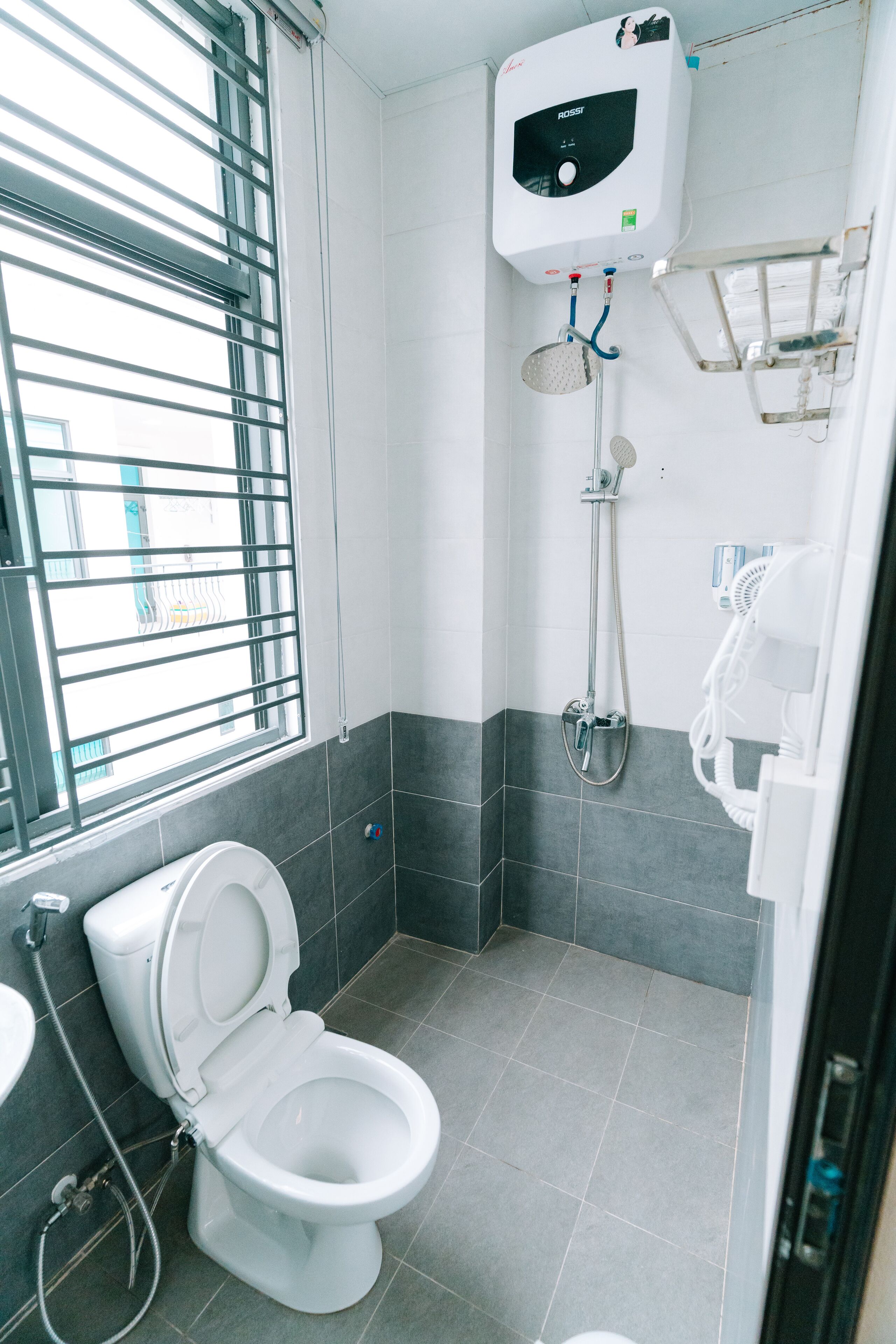 Un baño moderno con inodoro, ducha y ventana con persianas.