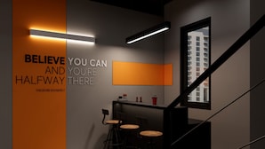 A modern interior with a motivational quote on the wall, a staircase, and a bar area with stools. - X-Stay (Hai Phong)