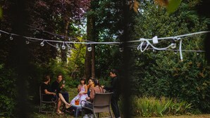 A group of people sitting on chairs outdoors with string lights overhead.