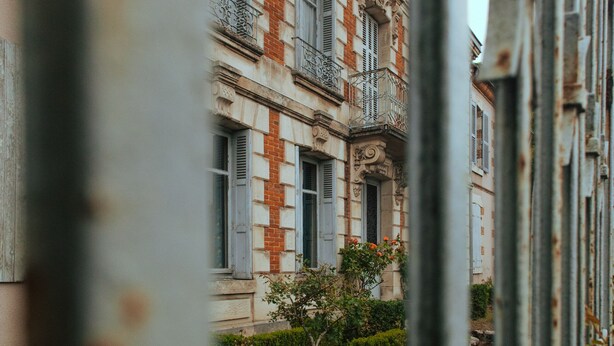 A historic building with a symmetrical facade, large windows, and a central balcony.