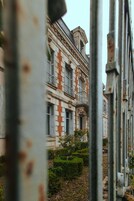 Um edifício histórico com fachada simétrica, janelas amplas e uma varanda central.