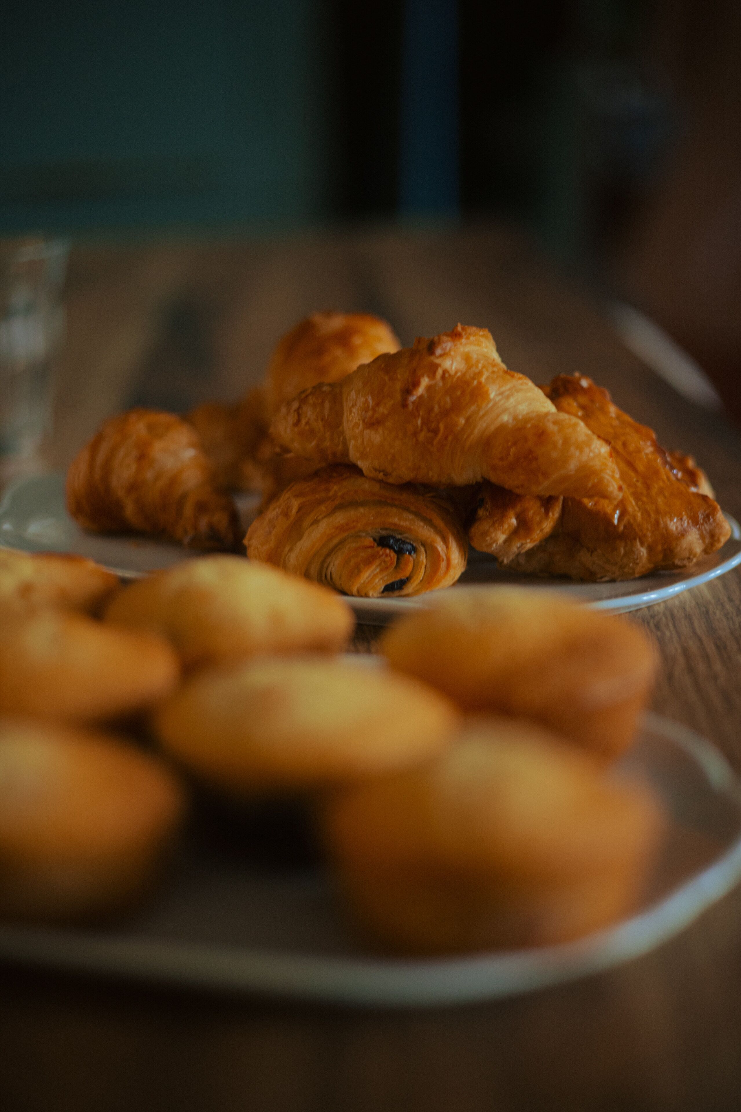 A plate of pastries, including croissants and other baked goods, on a wooden table.