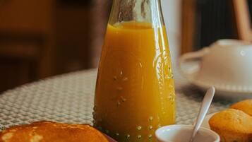 A breakfast setting with pancakes, a glass of orange juice, and a muffin on a table.