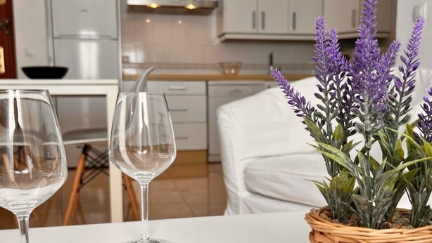 Una mesa de comedor con dos copas de vino vacías y una cesta de mimbre con plantas de lavanda.