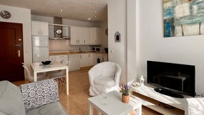 Una sala moderna con un sofá, un televisor y un comedor con una mesa y sillas.