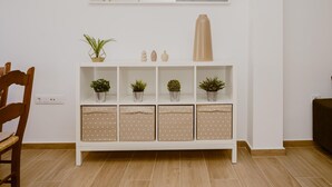 Una consola blanca con plantas en macetas, un florero y una lámpara.
