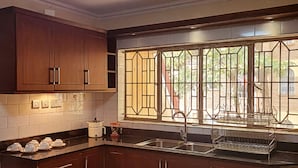 Eine Küche mit dunklen Holzausziehtüren, einer Spüle aus Edelstahl und einem Fenster mit Verzierungen.