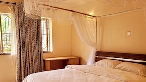 Ein Schlafzimmer mit einem hölzernen Bett, einem Nachttisch, einem Fenster mit Vorhängen und einer Decke mit dekorativem Baldachin.