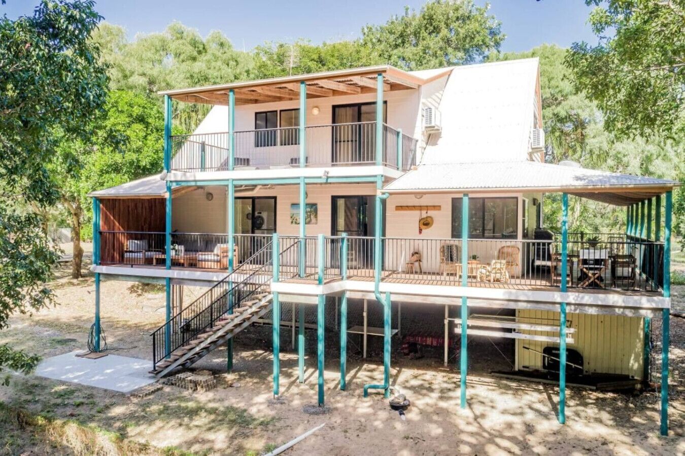 A two-story house with a balcony, outdoor seating, and a covered patio area.