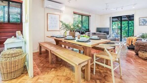 Un'area pranzo con un tavolo di legno apparecchiato per quattro persone, una panca e un divano sullo sfondo.