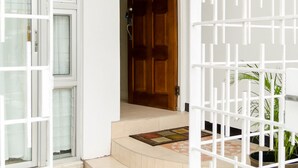 A clean entrance with a wooden door, a white gate, and a tiled floor. - Cityscape Living at Surbiton (Kingston)