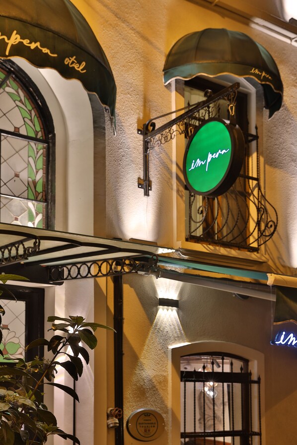 Un edificio con un letrero verde que dice "im perna otel" y un ventanal decorativo de vidrio.