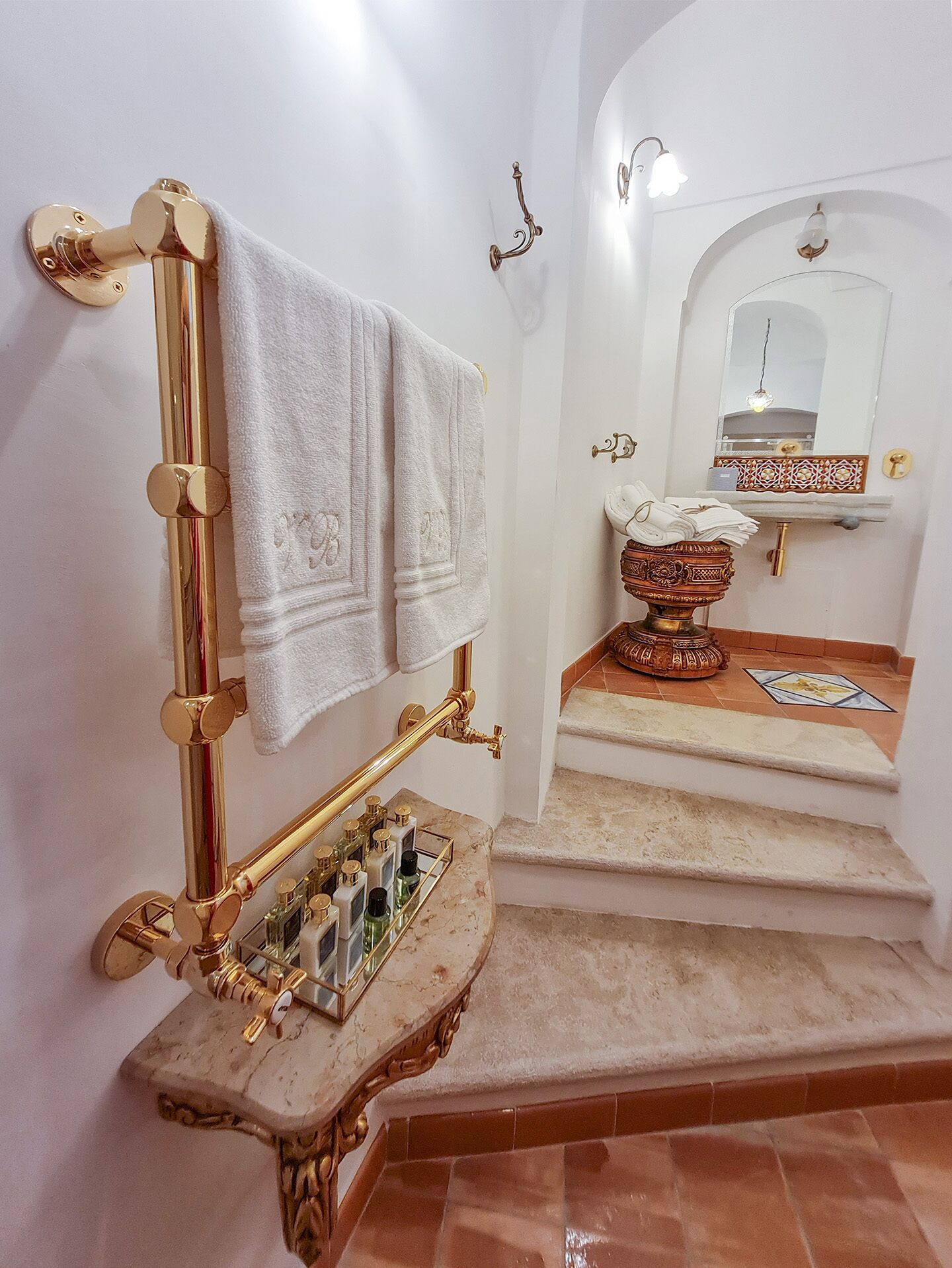 A bathroom with a golden towel rack, a marble sink, and a decorative bowl.