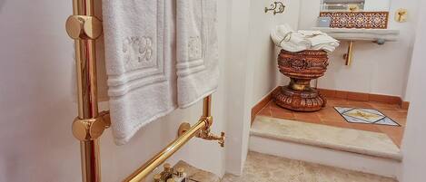 A bathroom with a golden towel rack, a marble sink, and a decorative bowl.