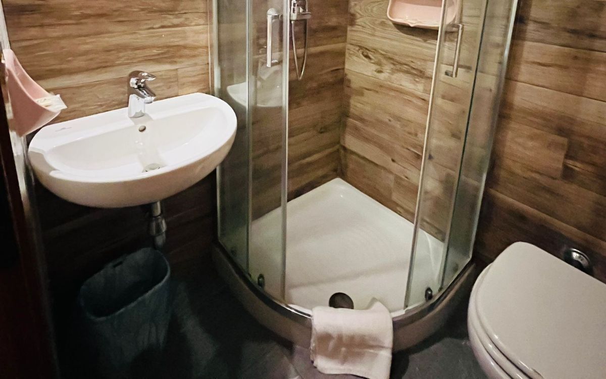 A bathroom with a glass-enclosed shower, a sink, and a toilet.