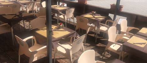 An outdoor cafe with tables and chairs, some with 'San Luis' branding.