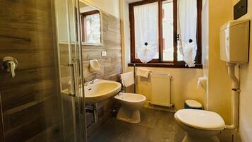 Un baño con cabina de ducha de vidrio, un lavamanos, un bidé y un inodoro.