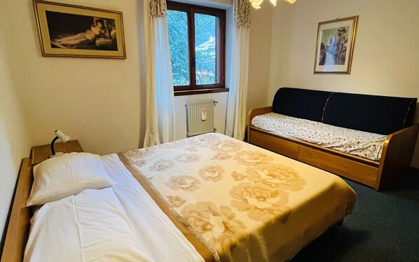 Un dormitorio con una cama, un banco de madera y dos cuadros en las paredes.