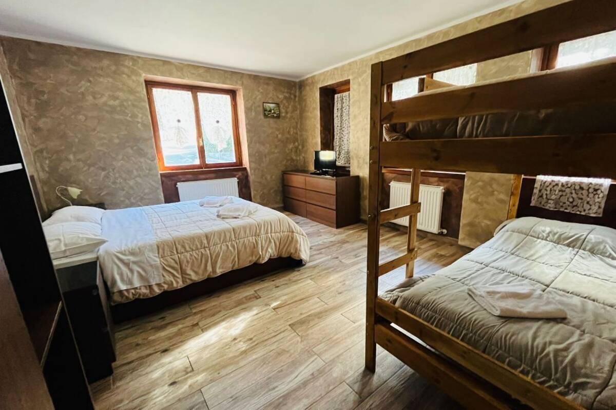 A bedroom with bunk beds, a dresser, a desk, and a window with curtains.