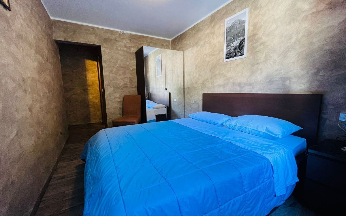 A bedroom with a large bed, a chair, a nightstand, and a mirror.