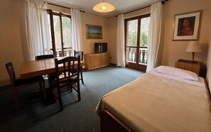 Una habitación con una cama, un escritorio con una silla, un televisor y una ventana con cortinas.