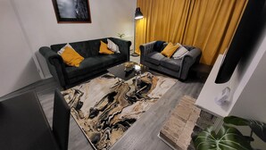 A modern living room with two sofas, a coffee table, a large abstract rug, and a framed picture on the wall. - Charming 2-bed Apartment in Grays (Grays)