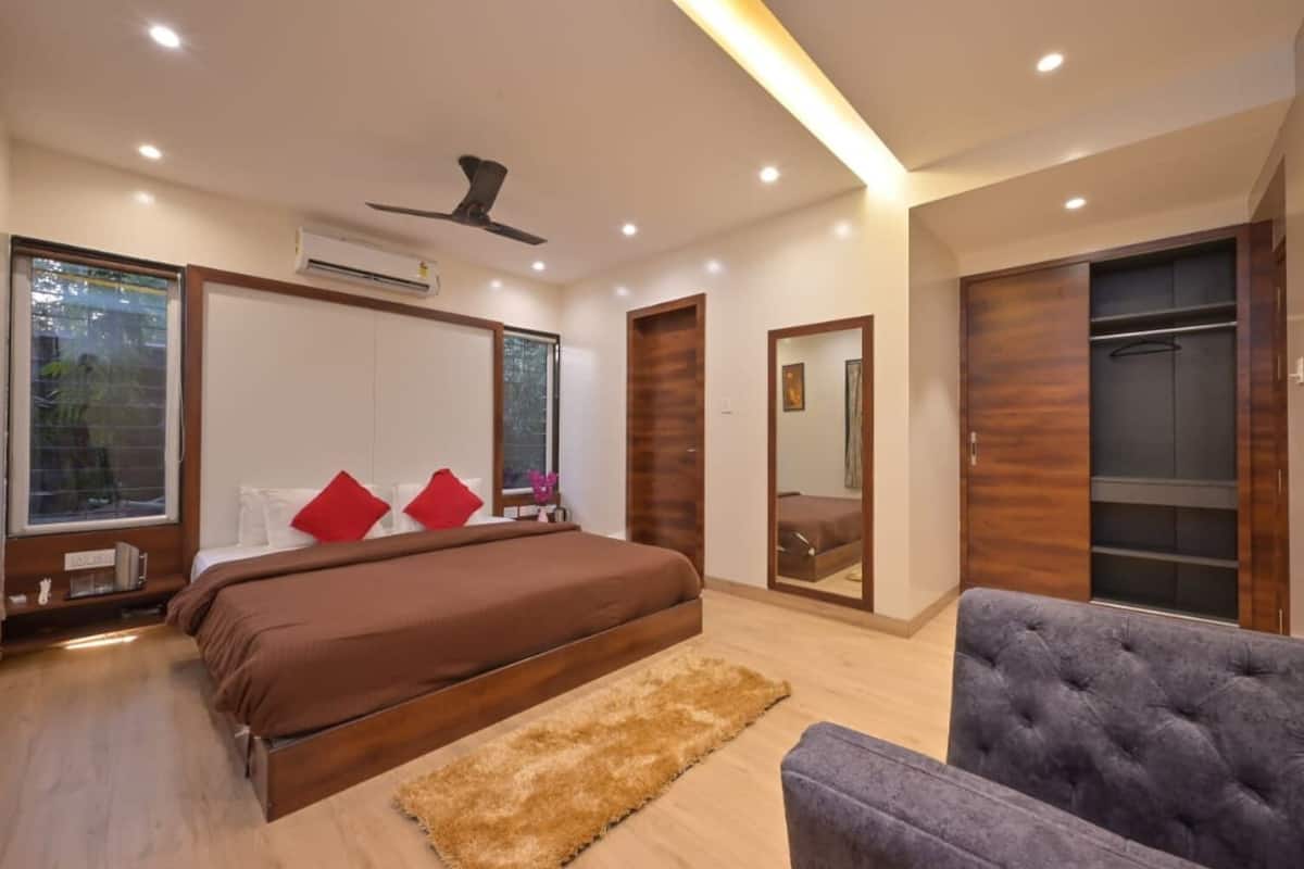 A modern bedroom with a large bed, a ceiling fan, and a wardrobe.